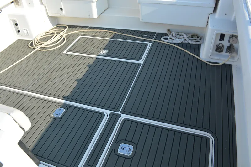 Slide: The Image of 1999 Pursuit 3400 Express boat deck with non-slip flooring and coiled rope. - 8