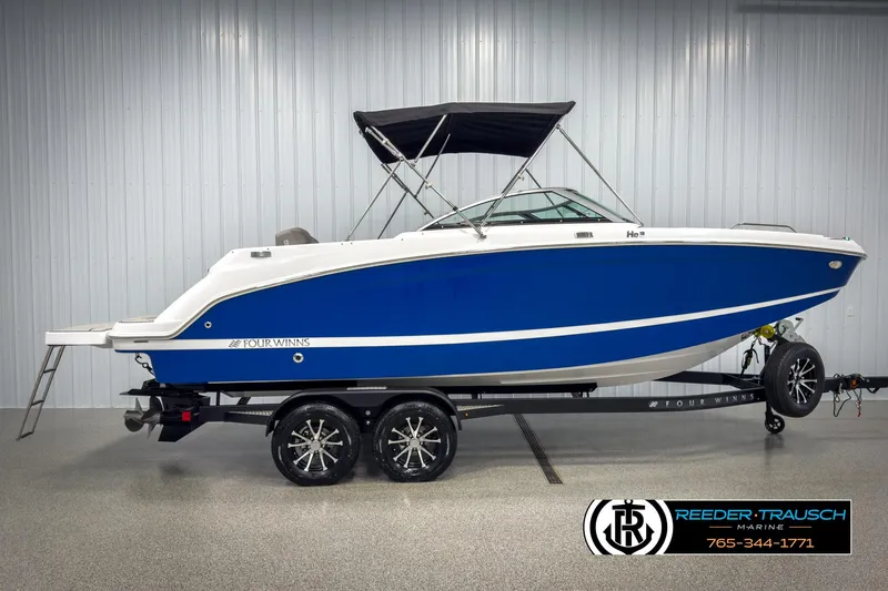 Slide: The Image of 2025 Four Winns HD3 boat in blue and white on a trailer, displayed indoors. - 5