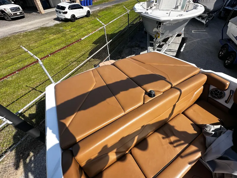 Slide: The Image of 2022 Axis A24 boat with tan leather seating, parked near a fence. - 12