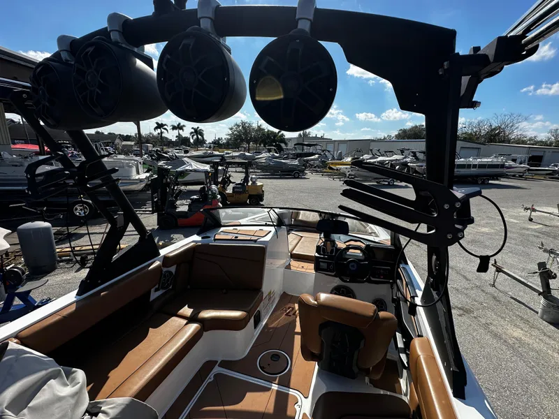 Slide: The Image of 2022 Axis A24 boat interior with speakers and seating, parked in a marina. - 13