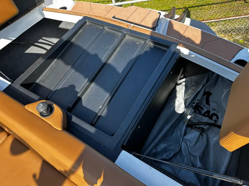 Slide: The Image of 2022 Axis A24 boat interior storage compartment with brown seating and black cover. - 22