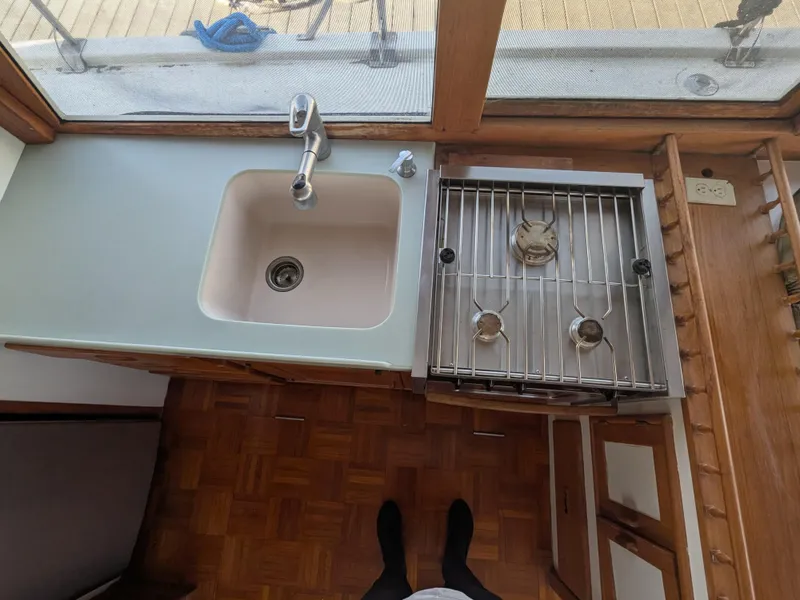 Slide: The Image of 1985 Roughwater 41 Pilothouse kitchen with sink and stove, wooden flooring. - 13