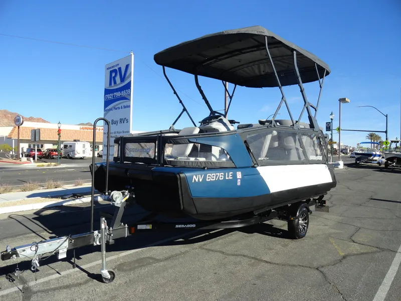 Slide: The Image of 2024 Sea-Doo Switch Sport 18 - 230 HP pontoon boat on trailer, parked outdoors. - 2