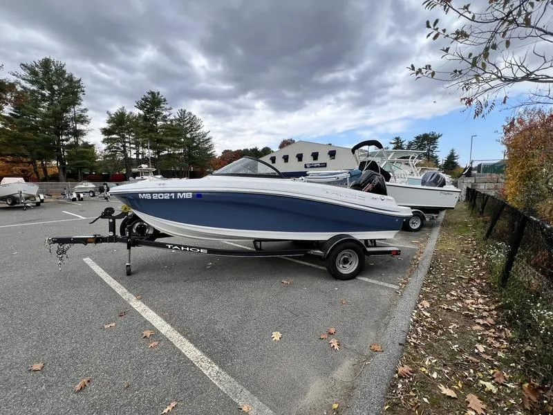 Slide: The Image of 2021 Tahoe 450 TS boat on trailer in parking lot, surrounded by trees and cloudy sky. - 5
