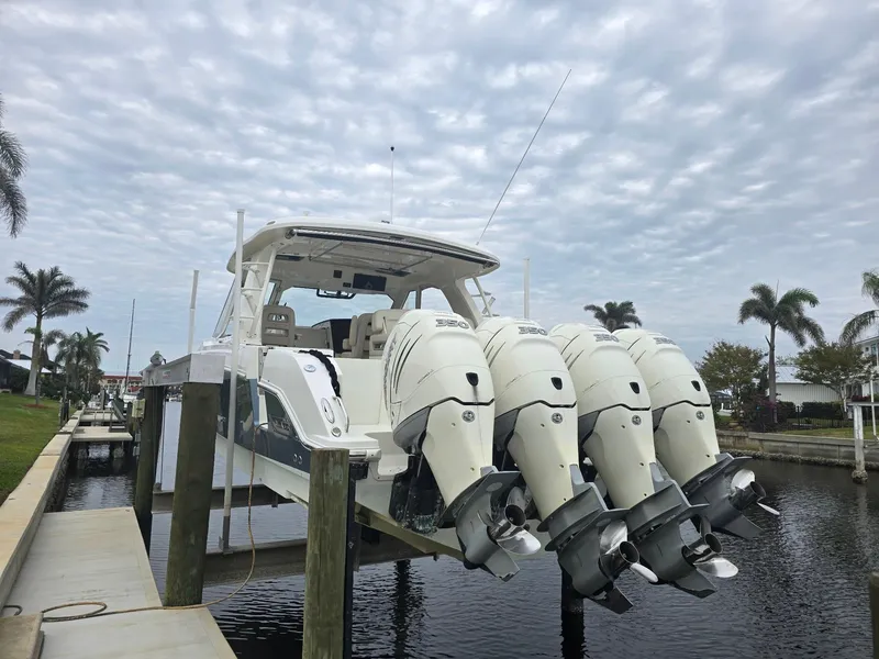 Slide: The Image of 2019 Boston Whaler 380 Realm with four outboard engines docked by palm trees. - 3