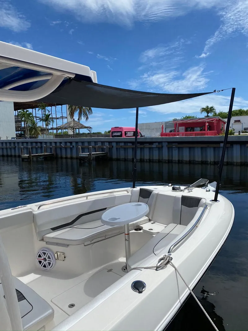 Slide: The Image of 2019 Wellcraft 242 Fisherman boat with canopy, docked under a clear blue sky. - 15