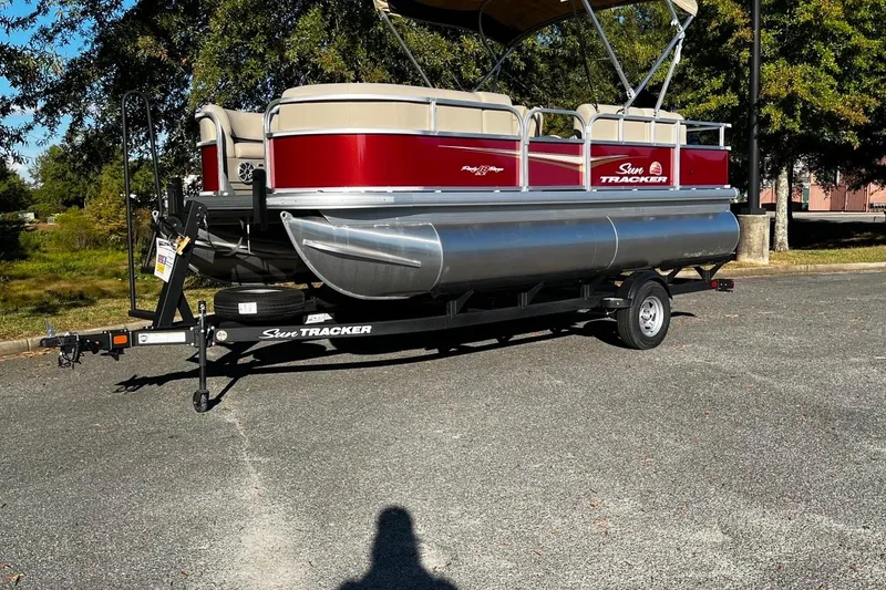 The Image of 2025 Sun Tracker Party Barge 18 DLX pontoon boat on trailer, parked outdoors. - 0