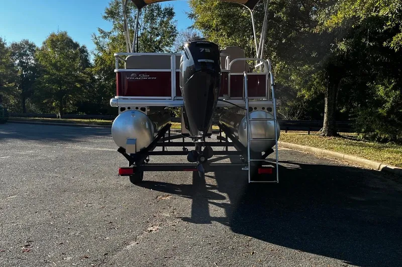 Slide: The Image of 2025 Sun Tracker Party Barge 18 DLX pontoon boat on trailer, parked outdoors. - 3
