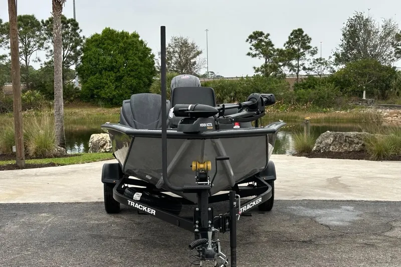 Slide: The Image of 2025 Tracker Pro Team 190 boat on trailer, parked near a scenic pond. - 2