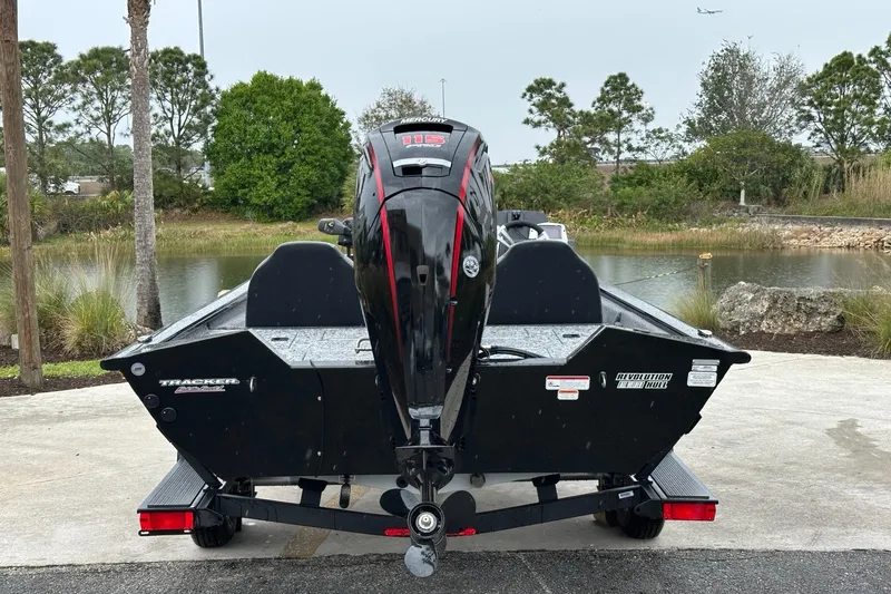 Slide: The Image of 2025 Tracker Pro Team 190 boat, rear view, parked near a scenic lake. - 3
