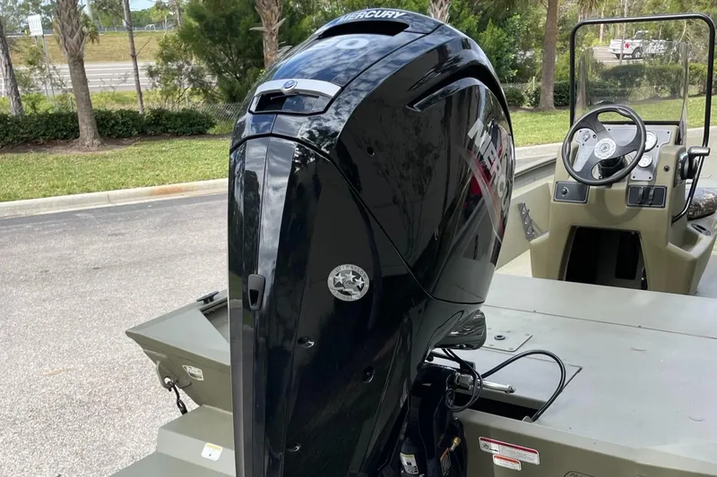 Slide: The Image of 2025 Tracker Grizzly 1860 CC boat with Mercury outboard motor, parked outdoors. - 3