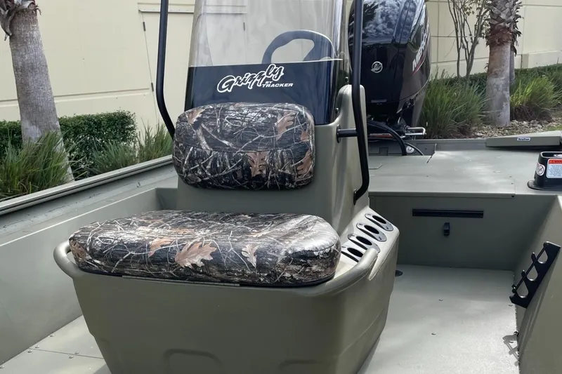 Slide: The Image of 2025 Tracker Grizzly 1860 CC boat with camo seats and console, outdoors. - 5