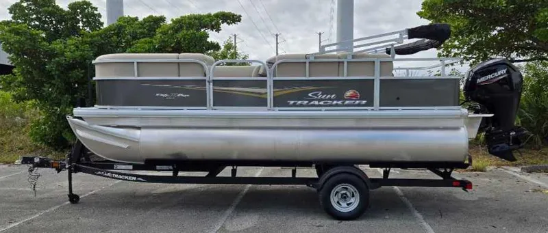The Image of 2025 Sun Tracker Party Barge 18 DLX pontoon boat on trailer, parked outdoors. - 0
