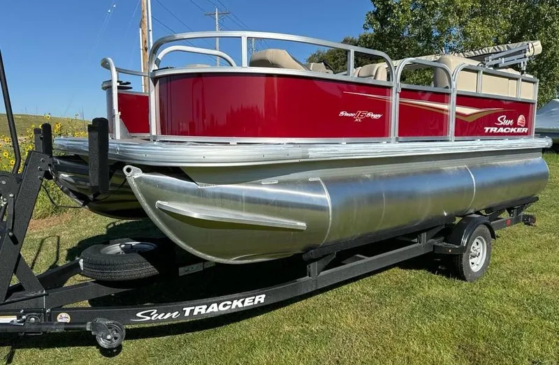 Slide: The Image of 2025 Sun Tracker Bass Buggy 16 XL Select pontoon boat on trailer, red and silver design. - 2