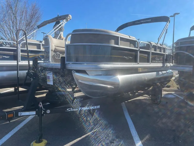 The Image of 2025 Sun Tracker Party Barge 18 DLX pontoon boat on trailer in parking lot. - 0