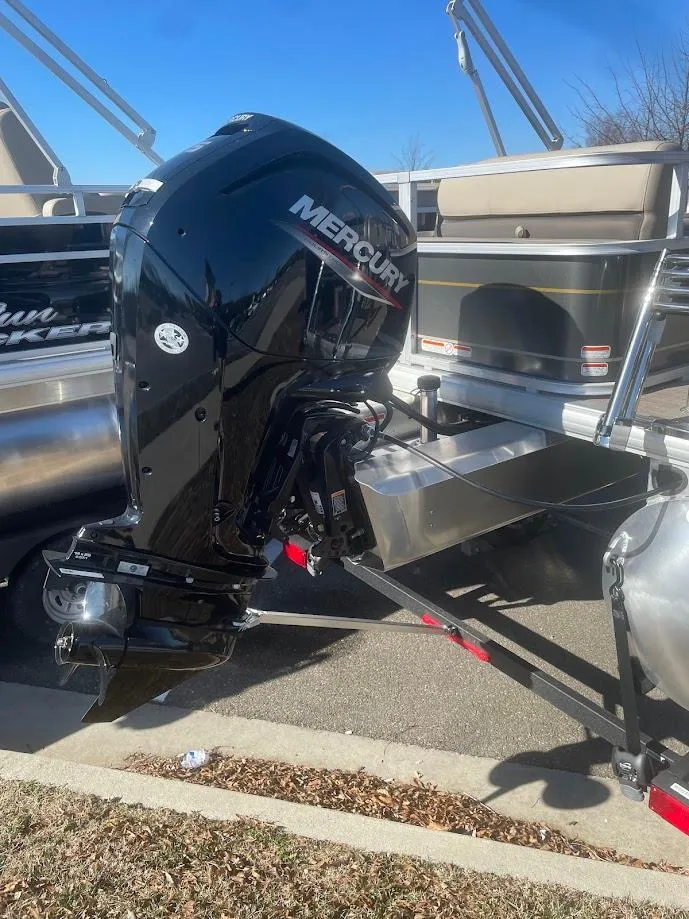 Slide: The Image of 2025 Sun Tracker Party Barge 18 DLX with Mercury outboard motor, parked on pavement. - 4