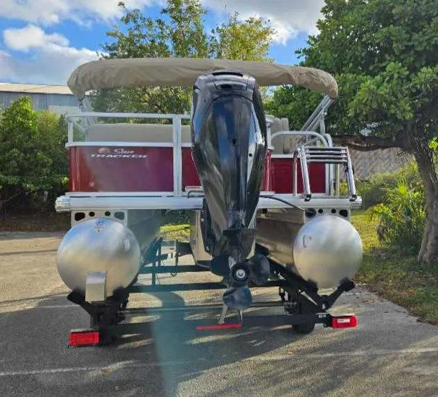Slide: The Image of 2025 Sun Tracker Party Barge 18 DLX pontoon boat with outboard motor, parked outdoors. - 11