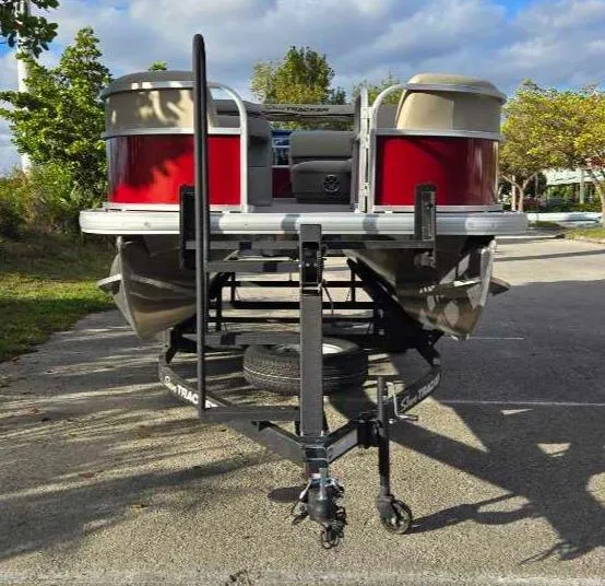 Slide: The Image of 2025 Sun Tracker Party Barge 18 DLX pontoon boat on trailer, parked outdoors. - 2