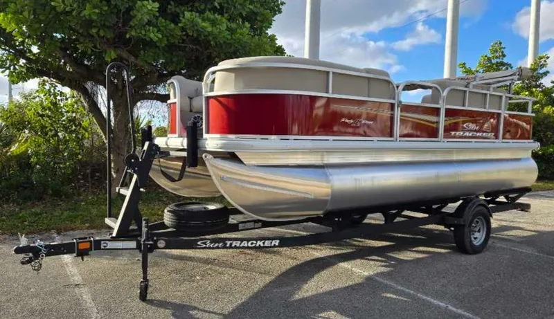 Slide: The Image of 2025 Sun Tracker Party Barge 18 DLX pontoon boat on trailer, parked outdoors. - 8
