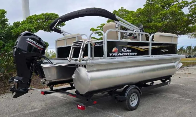 Slide: The Image of 2025 Sun Tracker Party Barge 16 DLX pontoon boat on trailer, parked outdoors. - 11
