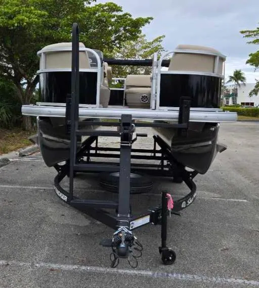 Slide: The Image of 2025 Sun Tracker Party Barge 16 DLX pontoon boat on trailer in parking lot. - 2