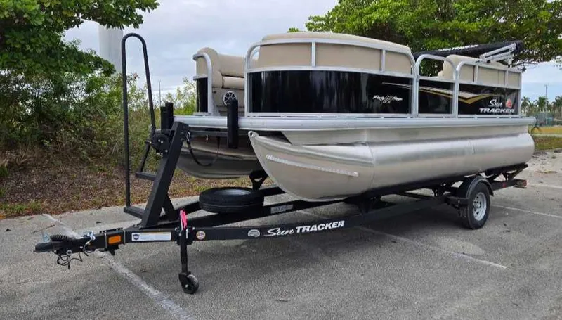 Slide: The Image of 2025 Sun Tracker Party Barge 16 DLX pontoon boat on trailer in parking lot. - 4