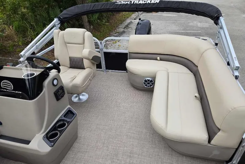 Slide: The Image of 2025 Sun Tracker Party Barge 16 DLX interior with beige seating and steering console. - 7