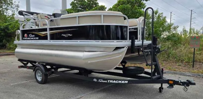 Slide: The Image of 2025 Sun Tracker Party Barge 16 DLX pontoon boat on trailer in outdoor setting. - 9