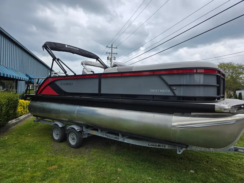 Slide: The Image of 2025 Godfrey SWEETWATER 2286 SFL pontoon boat on trailer, parked outdoors. - 1