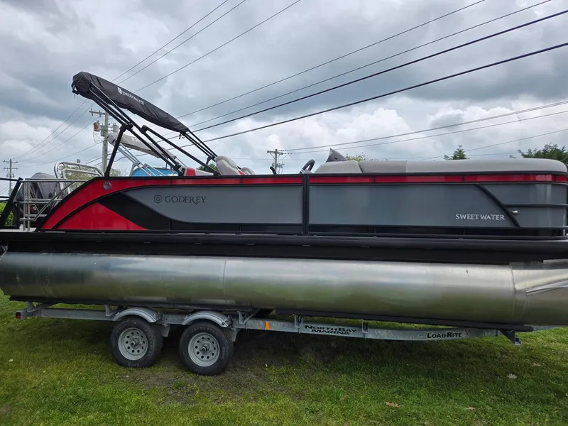 Slide: The Image of 2025 Godfrey SWEETWATER 2286 SFL pontoon boat on trailer, overcast sky. - 2