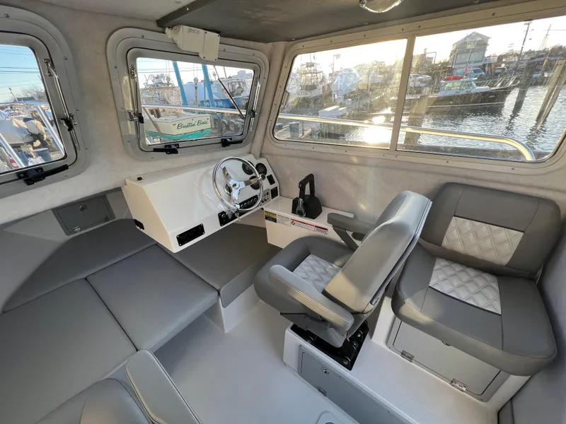 Slide: The Image of 2025 Defiance Admiral 220 EX boat interior with steering wheel and seating, docked at marina. - 20
