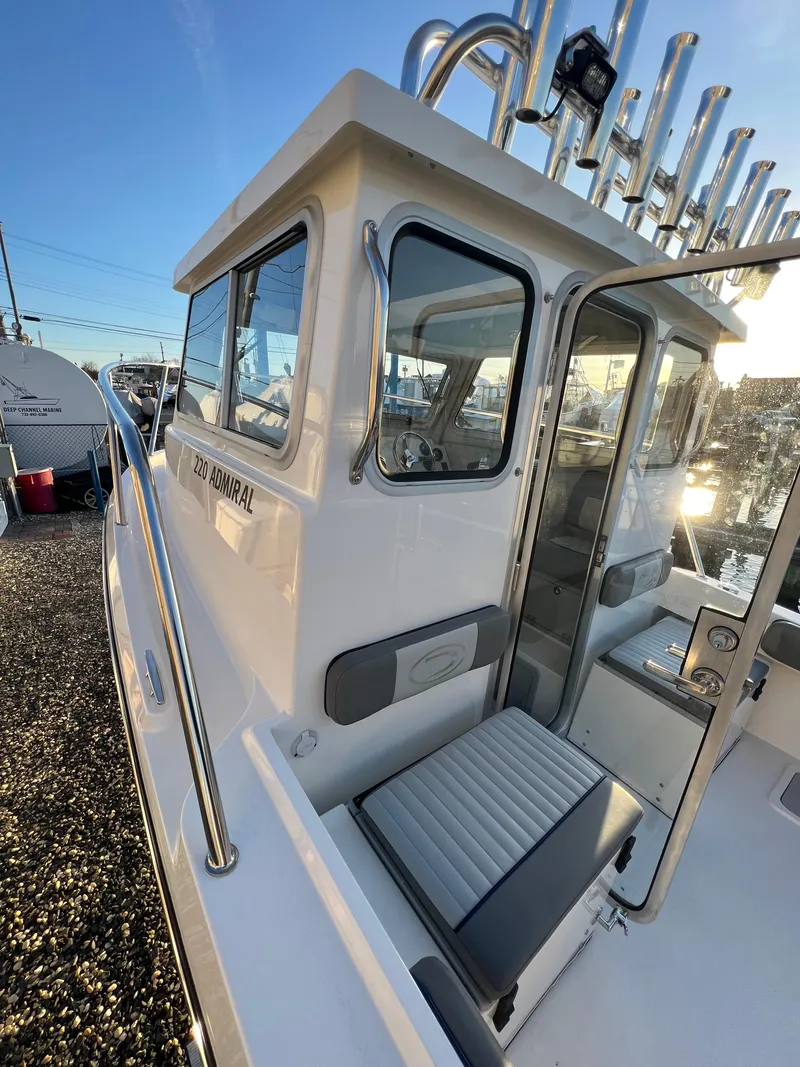 Slide: The Image of 2025 Defiance Admiral 220 EX boat, side view, docked under clear sky. - 30