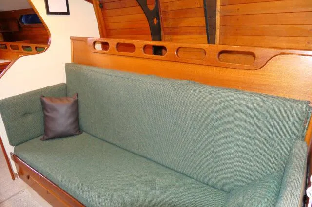 Slide: The Image of Interior of 1971 Ericson 39 Flush Deck with green sofa and wooden paneling. - 21