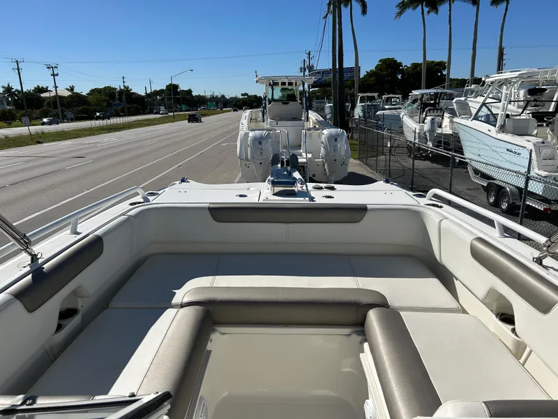 Slide: The Image of 2022 World Cat 255DC boat interior with seating, parked near a road and other boats. - 15