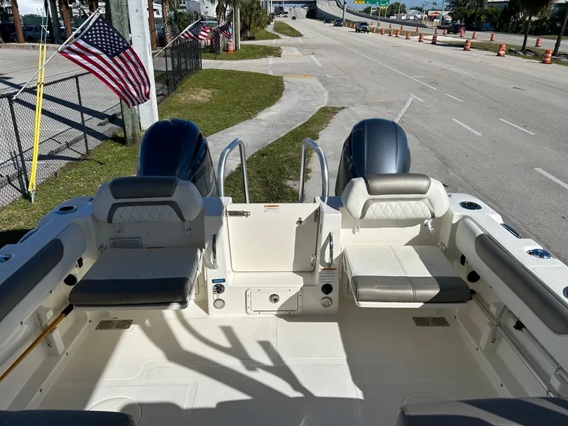 Slide: The Image of 2022 World Cat 255DC boat interior with dual engines, parked near American flags. - 17