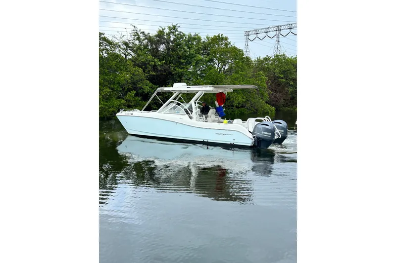 Slide: The Image of 2022 World Cat 255 DC boat cruising on calm water near lush greenery. - 2