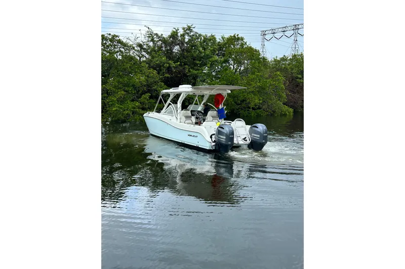 Slide: The Image of 2022 World Cat 255 DC boat cruising on a calm waterway with lush greenery. - 3