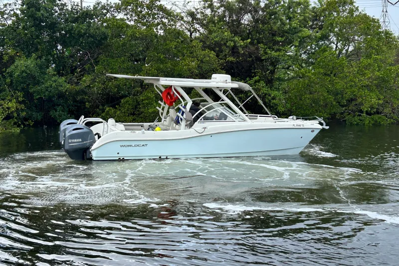 Slide: The Image of 2022 World Cat 255 DC boat cruising on a calm river with lush greenery. - 4