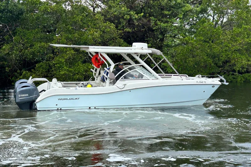 Slide: The Image of 2022 World Cat 255 DC boat cruising on water near lush greenery. - 5