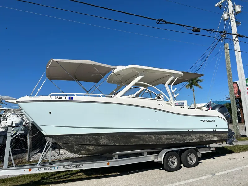 Slide: The Image of 2022 World Cat 255DC boat on trailer, parked outdoors under clear blue sky. - 6