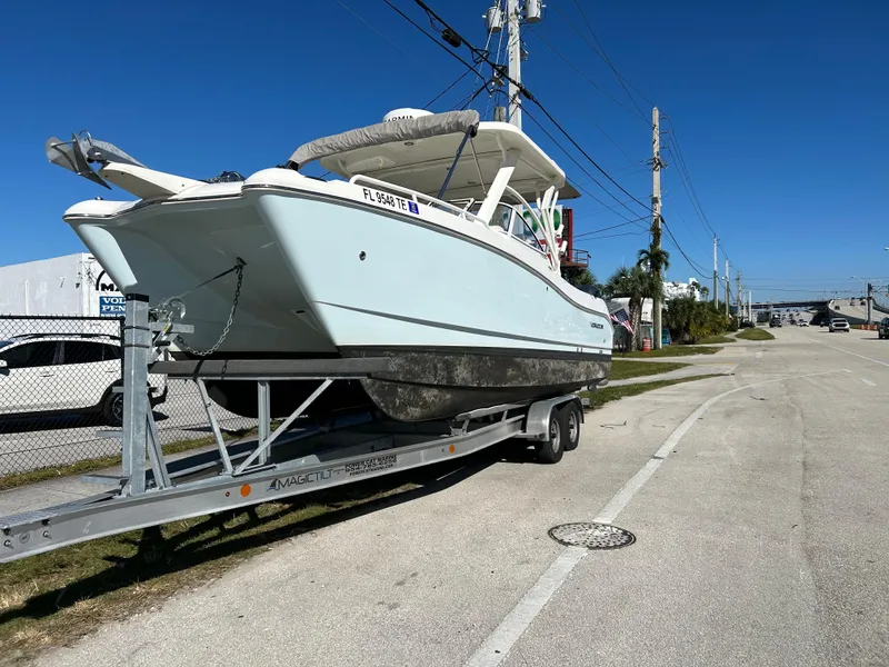 Slide: The Image of 2022 World Cat 255DC boat on trailer, parked on roadside under clear blue sky. - 7