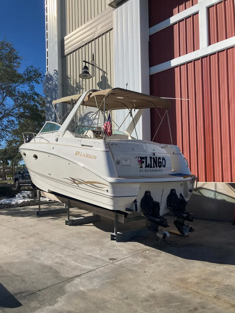 Slide: The Image of 2000 Larson Cabrio 290 boat on dry dock near a red and white building. - 20