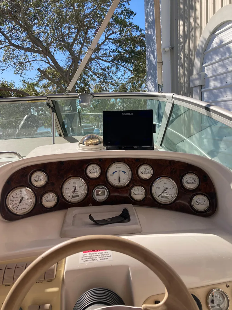 Slide: The Image of 2000 Larson Cabrio 290 dashboard with gauges and steering wheel, docked outdoors. - 24