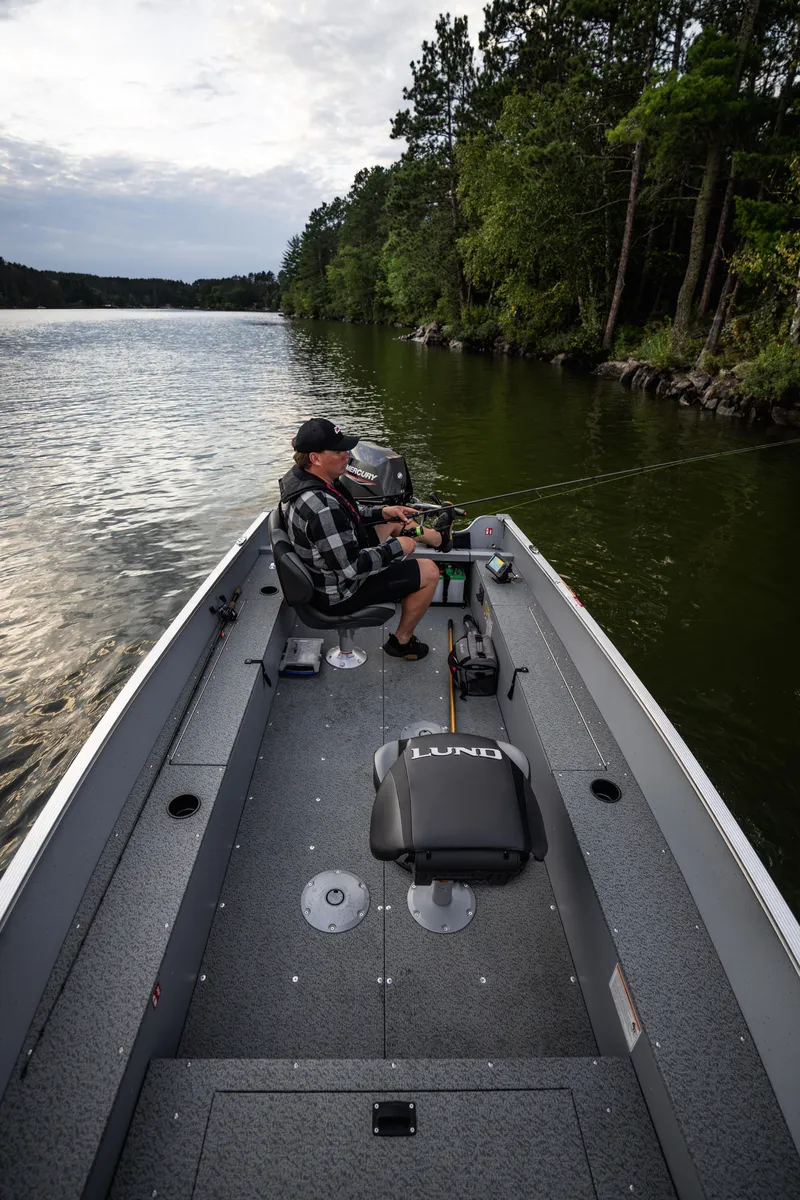 Slide: The Image of 2025 Lund 1600 Fury Tiller boat on a serene lake, surrounded by lush trees. - 10