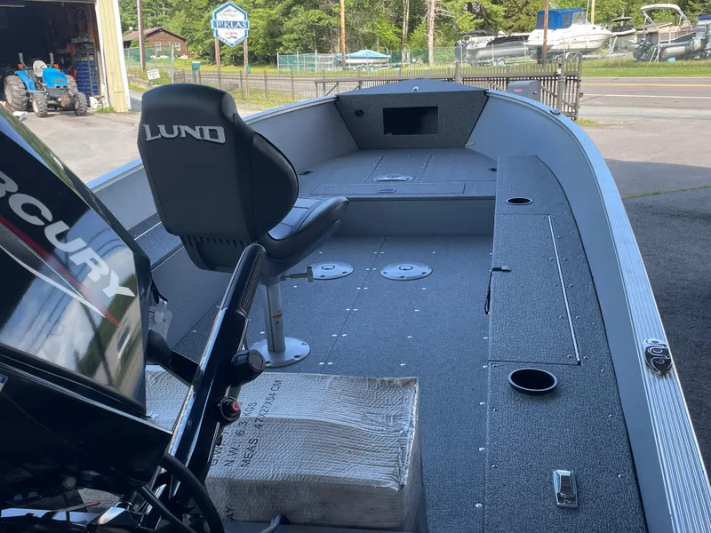 Slide: The Image of 2025 Lund 1600 Fury Tiller boat interior with Mercury engine, parked outdoors. - 12
