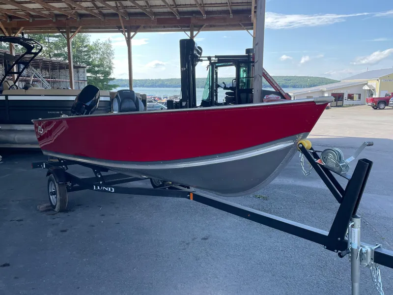 Slide: The Image of 2025 Lund 1600 Fury Tiller boat on trailer, parked under a shelter. - 4
