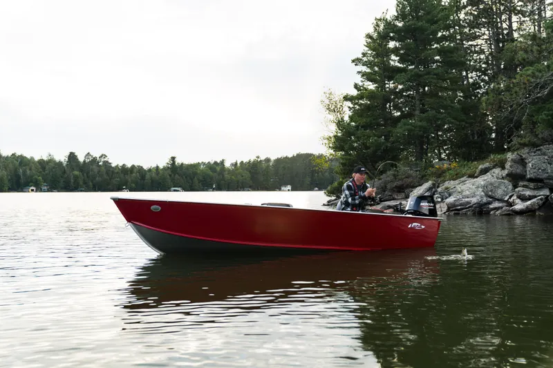 Slide: The Image of 2025 Lund 1600 Fury Tiller boat on a serene lake near a forested shoreline. - 6