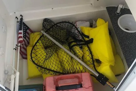 Slide: The Image of Storage compartment of 2021 Sea Pro 259 DLX with fishing gear and life jackets. - 13