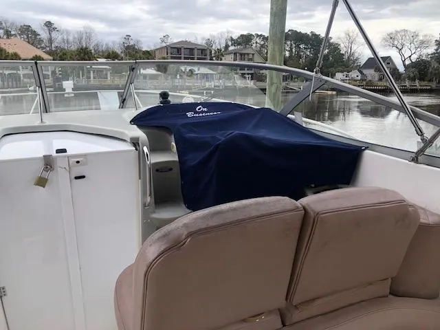 Slide: The Image of 2000 Bayliner 3055 Ciera boat interior with covered dashboard, docked by waterfront homes. - 14