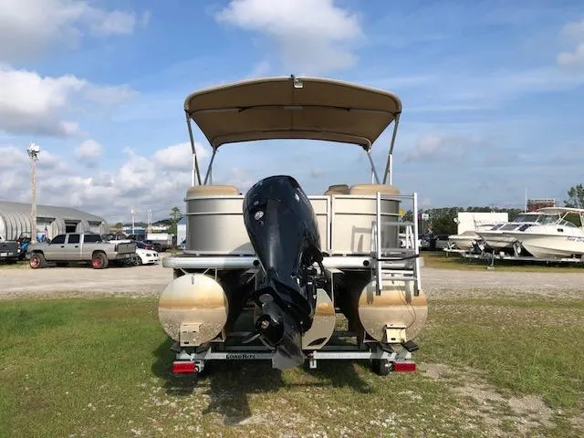 Slide: The Image of 2021 Sweetwater 2286 pontoon boat with canopy and outboard motor, parked on grass. - 5